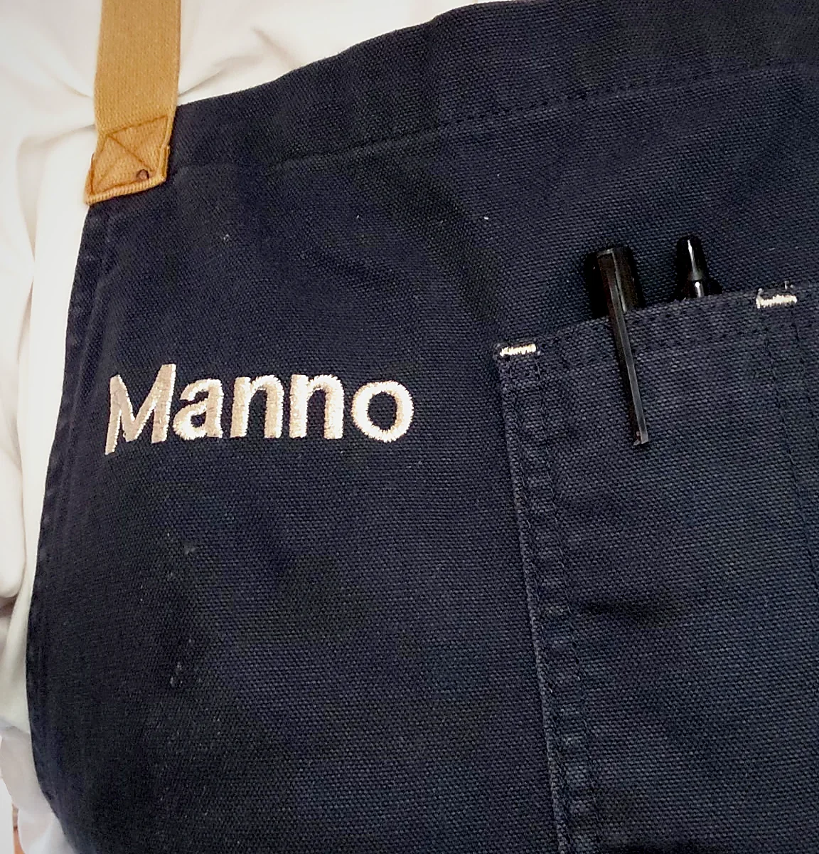 The pocket of Chef Manno's navy apron, embroidered with his name
