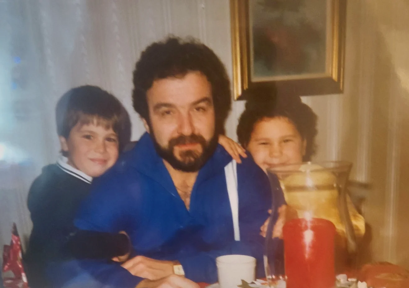 A family photograph of Michael Manno as a boy with his uncle, Chef James Naccarato, seated at a table with a red candle